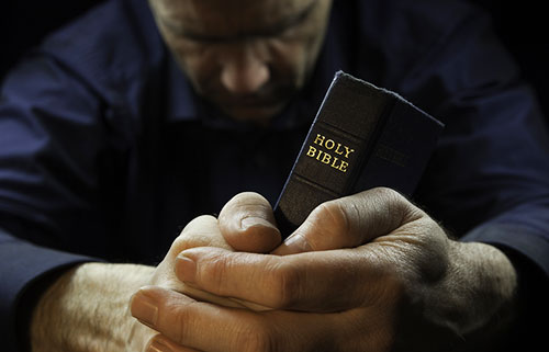مسيحي يصلي حاملا الانجيل