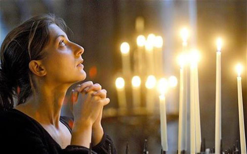 امرأة تصلي والشموع تظهر في الخلفية